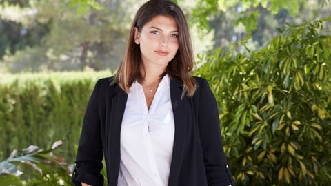 Business woman in front of green bushes and trees